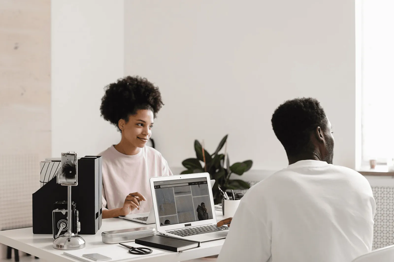 Two colleagues talking over a laptop in a bright office